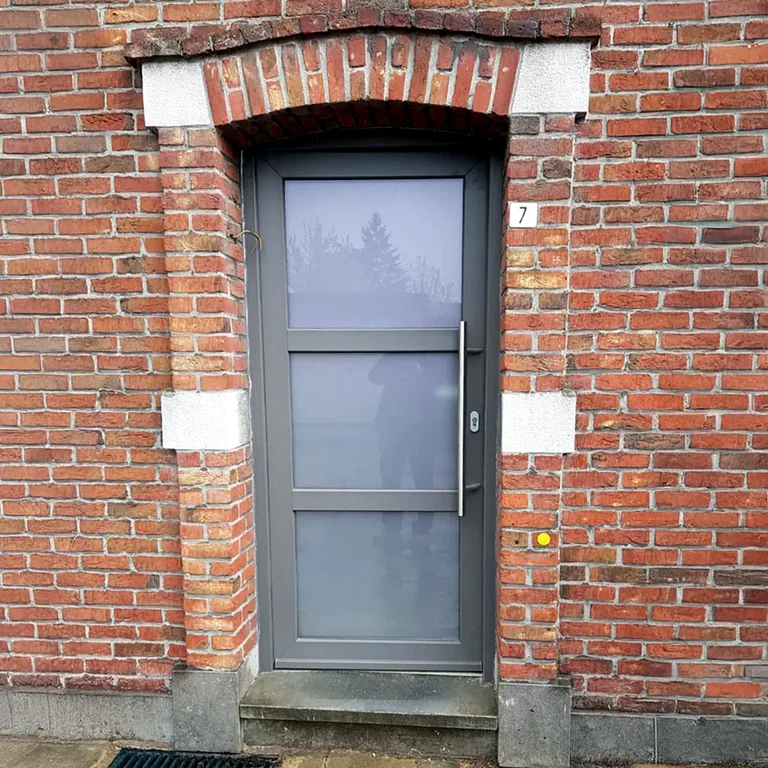 Antracietkleurige PVC voordeur in een bakstenen gevel