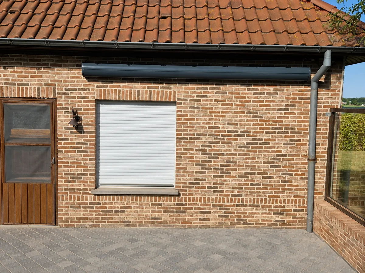 Dark cassette of a folding arm awning against a rural brick facade
