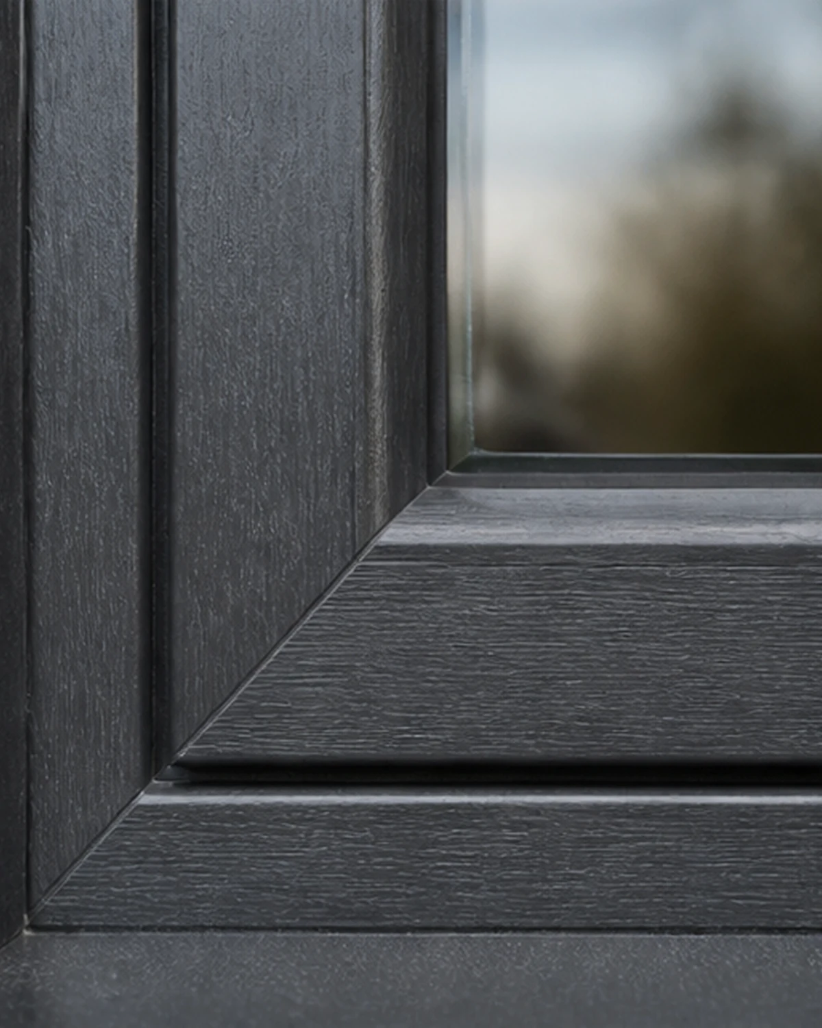 Fenêtre PVC anthracite avec film grain de bois et coins profilés soudés
