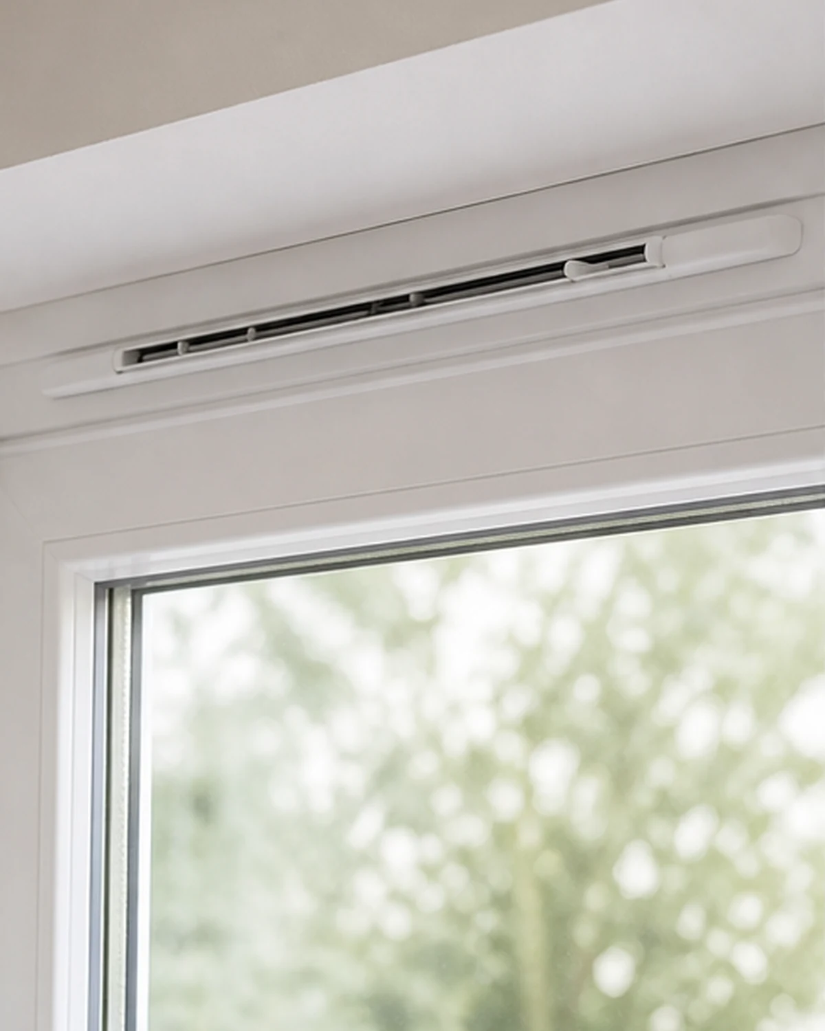 Adjustable ventilation grille at the top of a PVC window